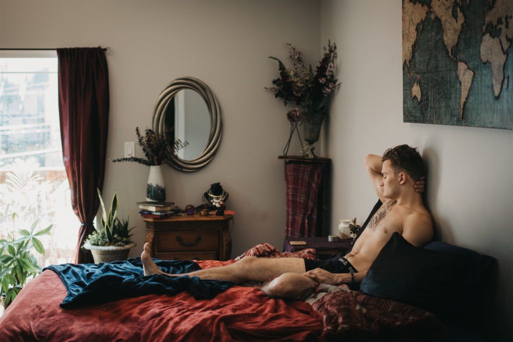 A man wearing underwear sitting in bed during a male boudoir photography session in Chicago.